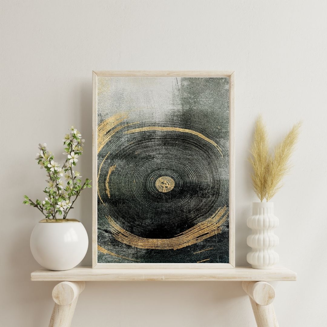 Framed abstract art piece on a shelf with decorative plants against a light wall.