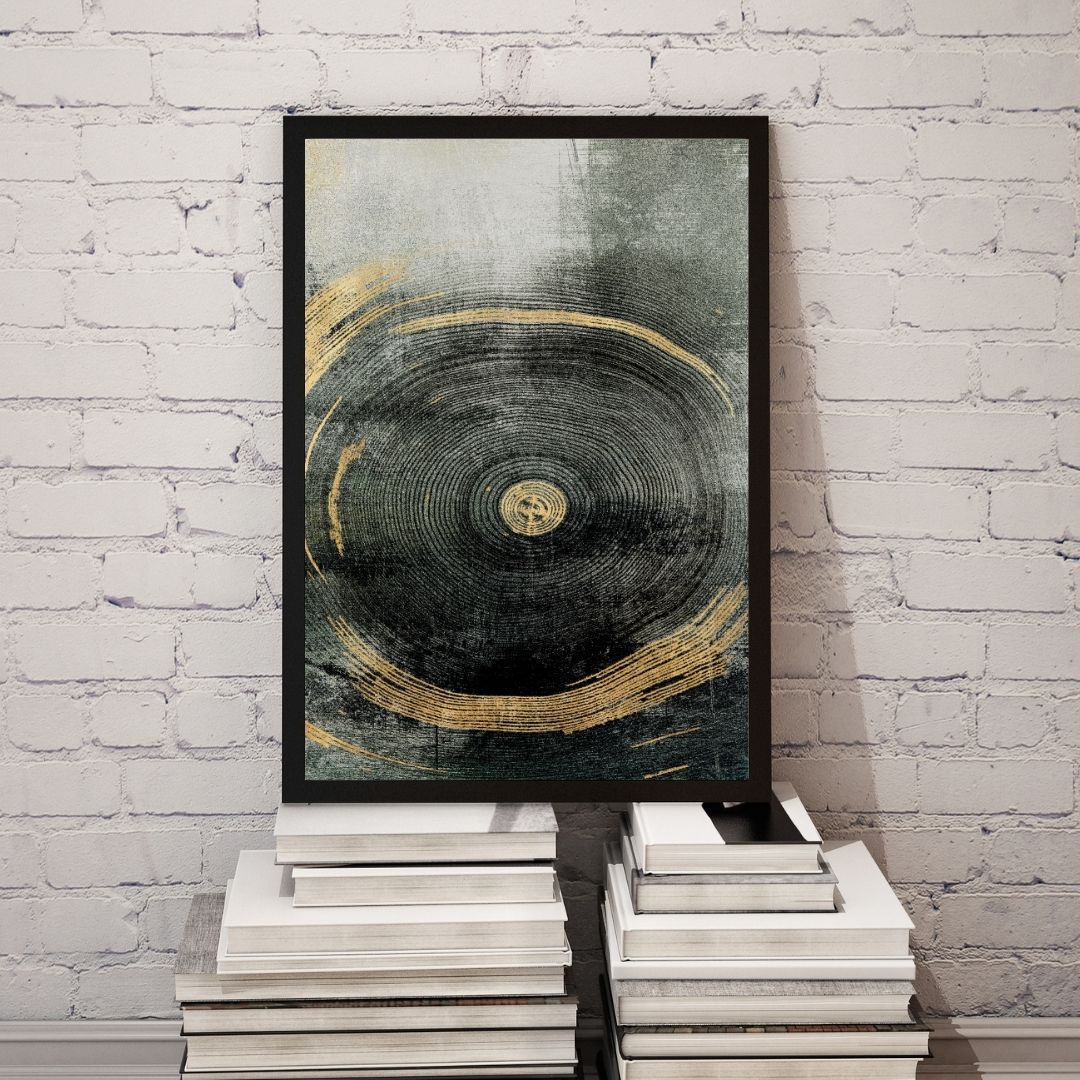 Framed abstract art piece with gold and black design on a white brick wall.