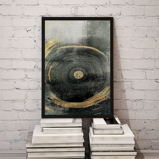 Framed abstract art piece with gold and black design on a white brick wall.