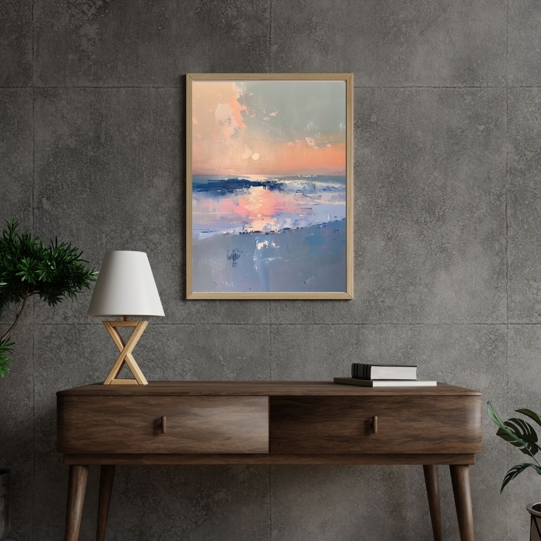 Framed abstract artwork above a wooden console table with a lamp and books against a gray wall.