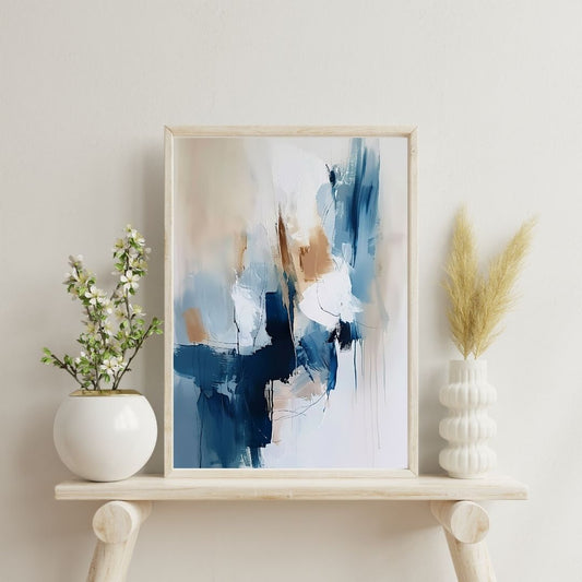 Framed abstract art piece on a shelf with decorative plants against a light wall.