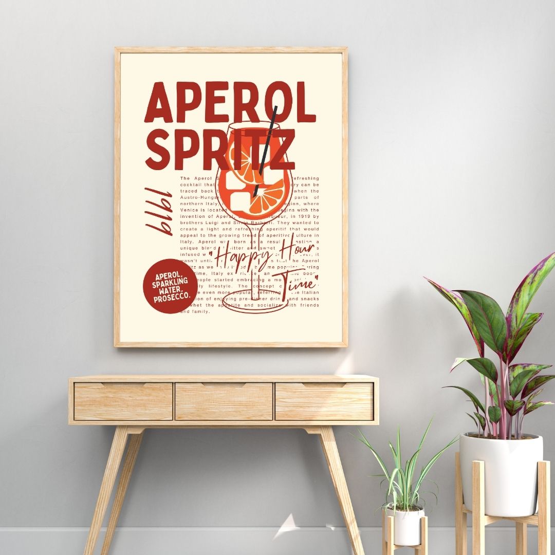 Framed Aperol Spritz recipe poster on a wall above a wooden console table with plants.