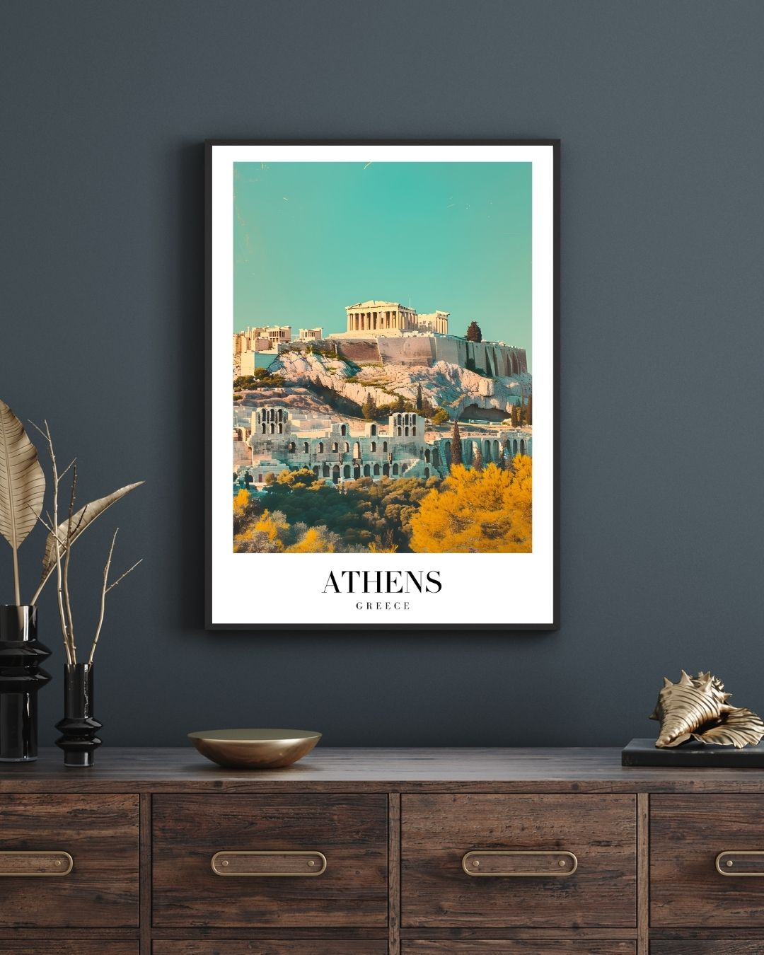 Framed Athens poster on a dark wall above a wooden cabinet.